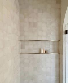 a bath room with a toilet and a tiled shower wall next to a window in the corner