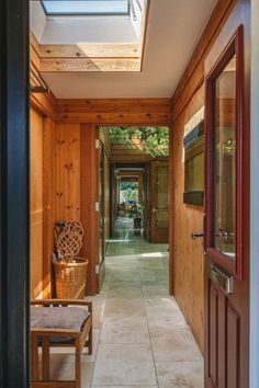 a hallway with wooden walls and doors leading to an outside room that has a skylight on the ceiling