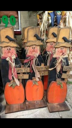 three scarecrows sitting on top of pumpkins in front of a store