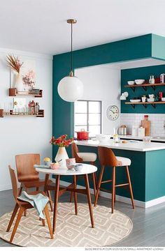 a kitchen with blue walls and wooden chairs in the center, white counter tops and shelves on the wall