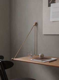 a desk with a lamp, book and glass on it in front of a wall