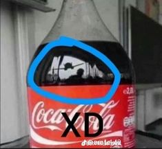 a coca - cola bottle sitting on top of a table with the word xd over it