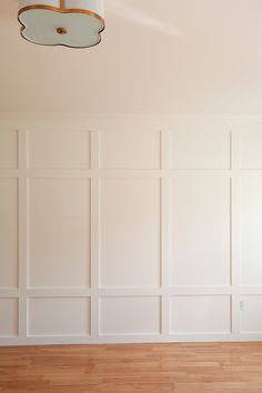 an empty room with white walls and wood flooring is pictured in this image, there are two lamps on the ceiling