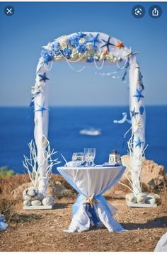 an outdoor wedding setup with blue and white flowers on the table, overlooking the ocean