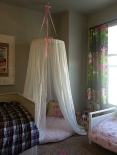 a canopy bed in a bedroom next to a window with curtains on the top and bottom