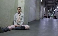 a woman sitting on the floor with her legs crossed in front of her face and wearing a scarf around her neck