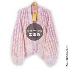 a pink knitted sweater hanging on a clothes hanger with the price tag below it