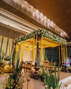 an elaborately decorated gazebo with flowers and greenery on the sides in a banquet hall