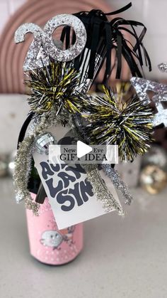 a pink bottle with some silver and black decorations in it on a table next to other items