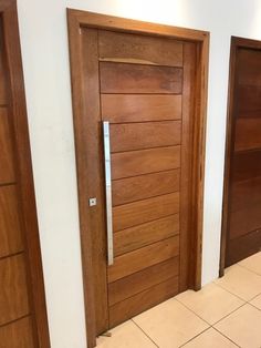 two wooden doors in a room with tile flooring and white walls on either side