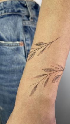 a woman's arm with a tattoo on it and an olive branch in the middle