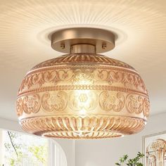 an ornately designed light fixture hangs from the ceiling in a room with white walls and windows