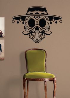 a green chair sitting in front of a wall with a skull wearing a sombrero