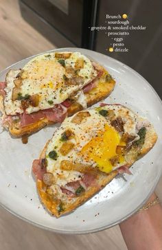 two pieces of toast with an egg and ham on it, sitting on a plate