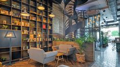 a living room filled with furniture and lots of bookshelves next to a spiral staircase