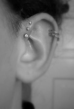 a woman's ear with three piercings on it