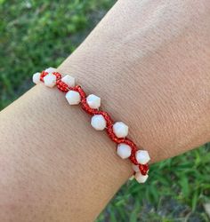 a person wearing a red and white beaded bracelet