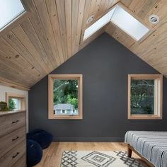 a bedroom with two windows and a rug on the floor in front of the bed