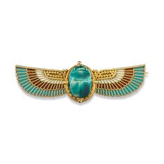 an egyptian scar with gold and turquoise stone in the shape of a scar on a white background