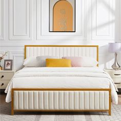 a white bed sitting next to a lamp on top of a wooden dresser in a bedroom