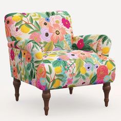 an upholstered chair with colorful flowers and leaves on the back, in front of a white background