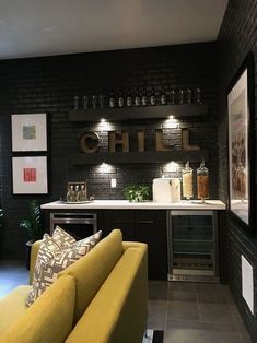 a yellow couch sitting in front of a bar with wine glasses on the back wall