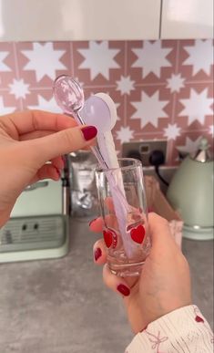 a woman holding a wine glass filled with liquid and heart shaped utensils in her hand