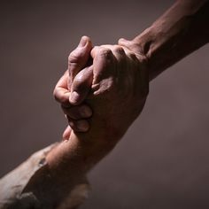 two hands holding each other over a piece of wood with one hand on the other