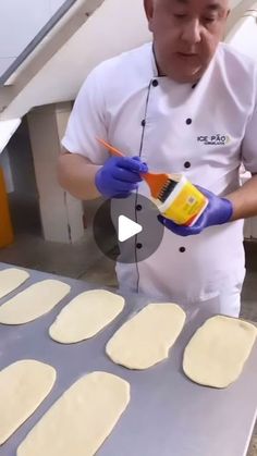 a man in white shirt and blue gloves making pizzas