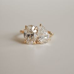 three pear shaped diamond rings sitting on top of each other, one in yellow gold and the other in white gold