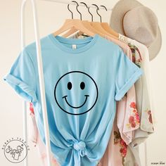 This happy hand-drawn smiley face is designed in a soft, cozy, lightweight t-shirt.  We hope you like it!  * 100% combed and ring-spun cotton (Heather colors contain polyester) * Fabric weight: 4.2 oz * Pre-shrunk fabric Refund/Exchange Policy: We do not accept returns or exchanges. Please refer to the sizing chart under the listed product to ensure you're selecting the best fit. Thank you! Fun Cotton T-shirt With Smiley Face, White Playful T-shirt With Smiley Face, White Smiley Face T-shirt, Funny Smiley Face T-shirt For Summer, Cute Cotton Tops With Smiley Face, Fun Smiley Face Tops, Funny Smiley Face Summer T-shirt, Smiley Face Graphic Tee With Short Sleeves, Fun Crew Neck Top With Smiley Face