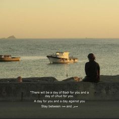 a person sitting on a wall looking out at the ocean with boats in the water