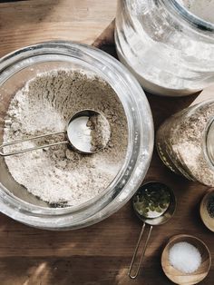 a wooden table topped with bowls filled with flour and measuring spoons next to each other