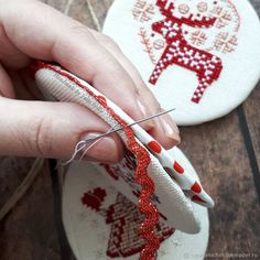 someone is using scissors to sew on some embroidered fabric with red and white designs