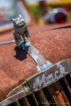 an old rusty car with a toy cat on the front grill and hood ornament