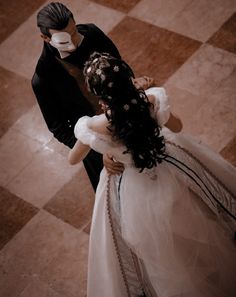 a man and woman dressed in costumes standing next to each other on a checkered floor