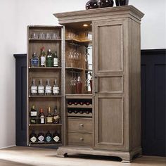 an armoire with wine glasses and liquor bottles in it, sitting on top of a hard wood floor