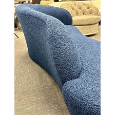 two blue couches sitting next to each other on a carpeted floor in a store