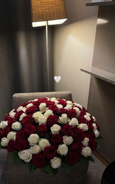 a large bouquet of red and white roses in a room with a lamp on the wall