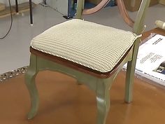 a wooden chair with a woven seat pad on the floor next to a bookcase