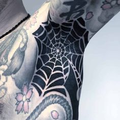 the back of a man's shoulder with tattoos on it and a spider web