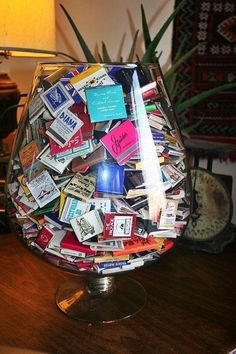 a glass vase filled with lots of different types of cards on top of a wooden table