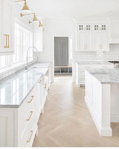 a large kitchen with white cabinets and marble counter tops