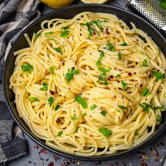 a bowl filled with pasta and garnished with parsley on the side next to lemons