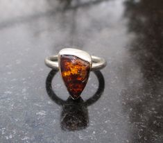 Handmade Raw Opal ring with triangle shaped rough Mexican opal in Rhyolite matrix.  This stone is dark Yellow to Orange with matrix visible and has some multi- color flash under bright light. *All 925 Sterling Silver  * Size 8 Ring  * Bezel set on a round band * Stone measurements : 5 x 14 x 8 mm * 4.35 Cts   This ring is ready to ship and If ordered you will receive the ring pictured.  Thanks for looking. All orders ship by USPS First Class / International Package Mail.  USPS Priority Mail shipping and Priority Express mail are also available at checkout for orders to US addresses. Raw Opal Ring, Mexican Opal, October Birthstone Rings, Birthstone Rings, Raw Opal, Ring Pictures, Handmade Rings, October Birthstone, Opal Ring