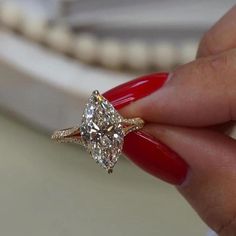 a woman's hand holding a ring with a large diamond on the middle of it