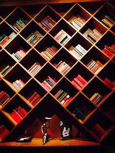 a bookshelf filled with lots of books on top of a wooden shelf next to a vase