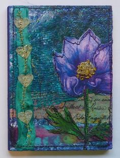 a purple flower sitting on top of a blue and green piece of art with gold accents