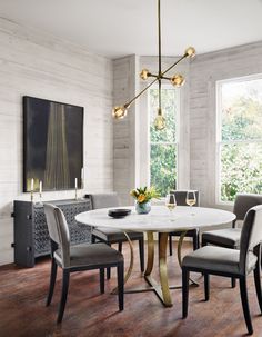 a dining room table with four chairs and a vase on the table next to it