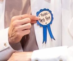 a person wearing a white shirt with a blue ribbon around the neck and badge on it